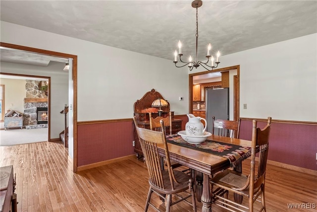 8345 Lapp Rd, Clarence, NY 14051 - dining room featuring light wood-type flooring, a chandelier, wainscoting, and a fireplace