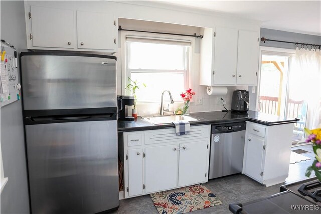 1422 Master St, North Tonawanda, NY 14120 - kitchen featuring stainless steel appliances, dark countertops, white cabinets, and a peninsula
