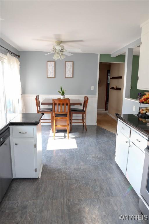 1422 Master St, North Tonawanda, NY 14120 - kitchen featuring ceiling fan, white cabinetry, a wainscoted wall, dishwasher, and dark floors