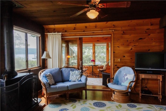 3271 Lanning Rd, Spafford, NY 13152 - living area with wood finished floors, wood walls, ceiling fan, a wood stove, and wooden ceiling
