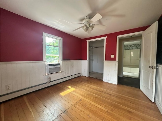 55 Maple St, Canisteo, NY 14823 - unfurnished bedroom featuring wainscoting, a baseboard radiator, light wood-style floors, cooling unit, and ceiling fan
