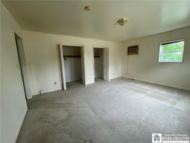 102 Broadhead Ave, Jamestown, NY 14701 - unfurnished bedroom featuring two closets, a wall mounted AC, and light colored carpet
