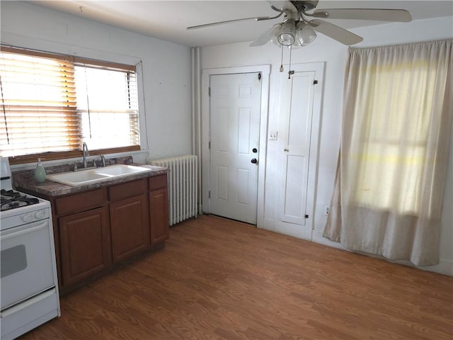 17 Lake St, Mount Morris, NY 14510 - kitchen featuring white range with gas stovetop, radiator heating unit, dark countertops, ceiling fan, and wood finished floors