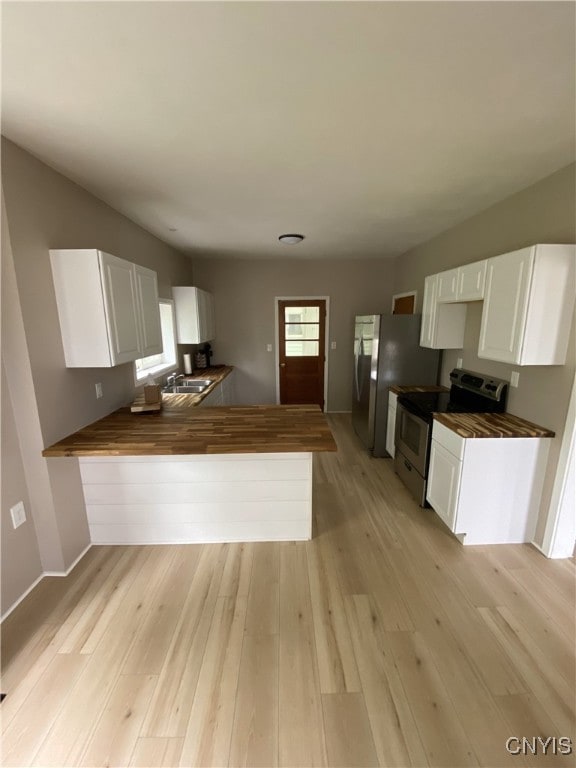 409 W 1st St S, Fulton, NY 13069 - kitchen featuring appliances with stainless steel finishes, wood counters, white cabinets, light wood-style flooring, and a peninsula