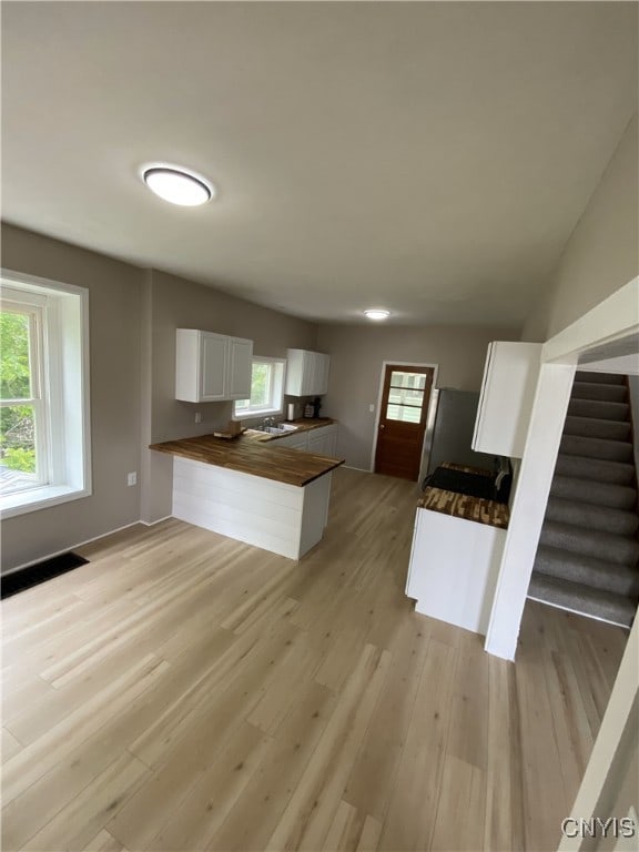409 W 1st St S, Fulton, NY 13069 - kitchen with butcher block countertops, a peninsula, light wood-type flooring, white cabinets, and healthy amount of natural light