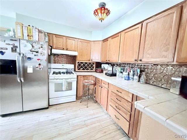19 Elm Ave, Homer, NY 13077 - kitchen with stainless steel refrigerator with ice dispenser, white range with gas cooktop, under cabinet range hood, backsplash, and tile counters