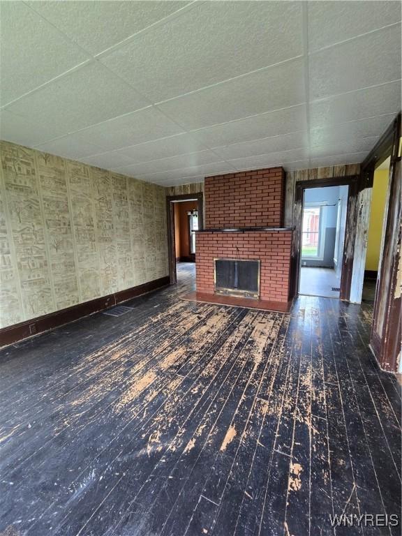 213 Highland Ave, Shelby, NY 14103 - unfurnished living room featuring a drop ceiling, wood-type flooring, and a fireplace