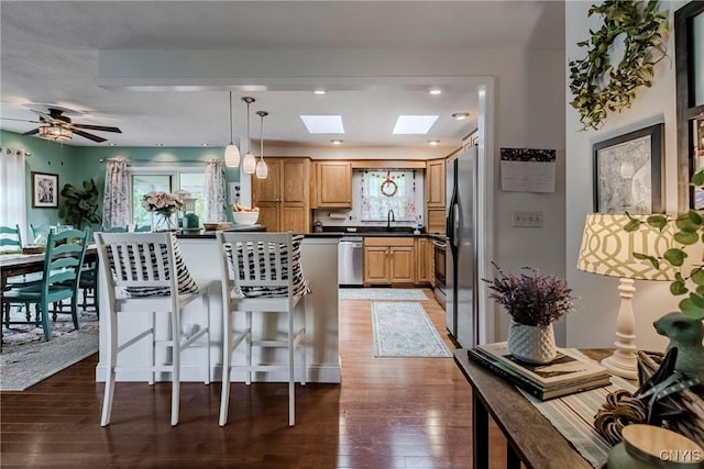 8272 Northgate Dr, Rome-Outside, NY 13440 - kitchen with dark countertops, a skylight, light wood-style flooring, appliances with stainless steel finishes, and a breakfast bar