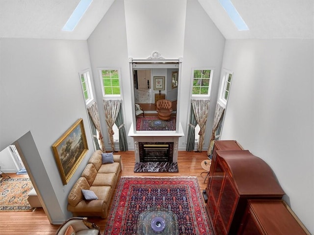 1010 Plank Rd, Penfield, NY 14580 - living area with a skylight, high vaulted ceiling, wood finished floors, healthy amount of natural light, and a fireplace with flush hearth