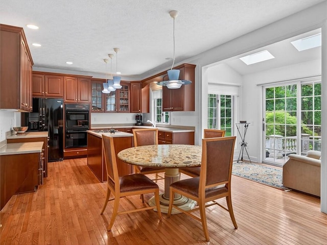 1010 Plank Rd, Penfield, NY 14580 - kitchen with black appliances, a kitchen island, light wood-style flooring, light countertops, and vaulted ceiling