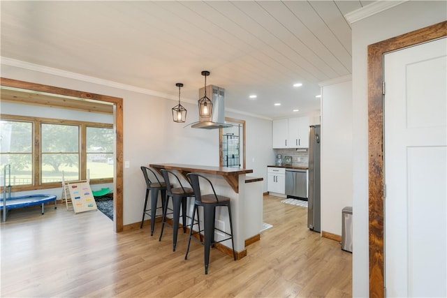 7046 Safford Ave Unit 12, Castile, NY 14530 - kitchen with appliances with stainless steel finishes, crown molding, island exhaust hood, a kitchen breakfast bar, and white cabinets