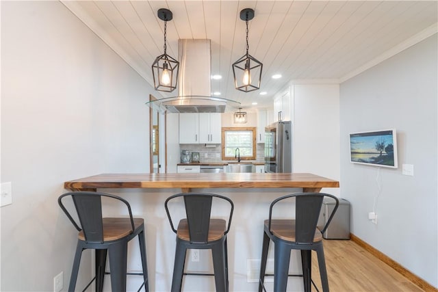 7046 Safford Ave Unit 12, Castile, NY 14530 - kitchen featuring wooden counters, island range hood, appliances with stainless steel finishes, white cabinetry, and a kitchen bar
