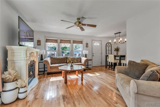 4306 Shimerville Rd, Clarence, NY 14031 - living area featuring a chandelier, ceiling fan, light wood-style flooring, a baseboard heating unit, and a glass covered fireplace