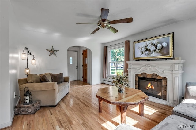 4306 Shimerville Rd, Clarence, NY 14031 - living area with arched walkways, a baseboard heating unit, ceiling fan, light wood finished floors, and a tile fireplace