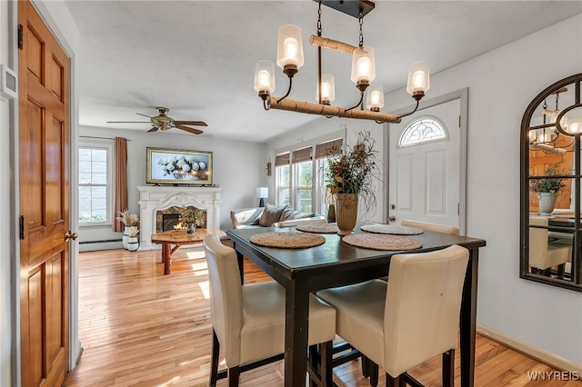 4306 Shimerville Rd, Clarence, NY 14031 - dining room with light wood-style flooring, ceiling fan, a warm lit fireplace, and a chandelier
