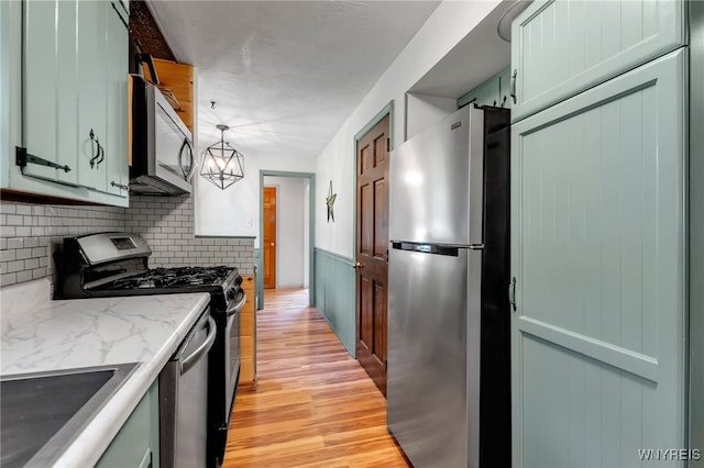 4306 Shimerville Rd, Clarence, NY 14031 - kitchen featuring appliances with stainless steel finishes, light wood-style floors, backsplash, light stone counters, and pendant lighting