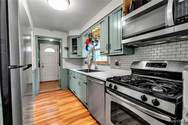 4306 Shimerville Rd, Clarence, NY 14031 - kitchen with appliances with stainless steel finishes, green cabinetry, light wood-type flooring, light countertops, and backsplash