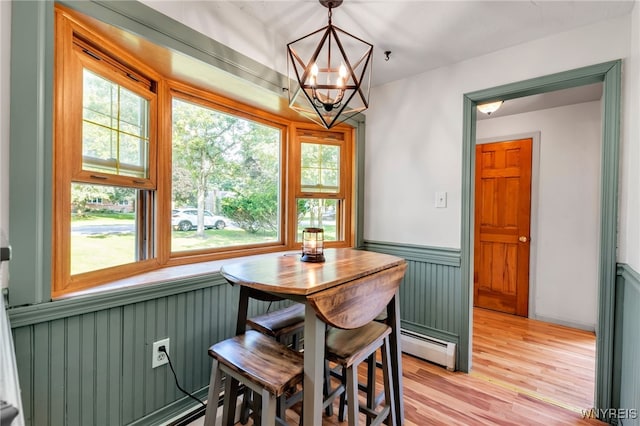 4306 Shimerville Rd, Clarence, NY 14031 - dining area with a baseboard radiator, a chandelier, a wainscoted wall, and light wood finished floors