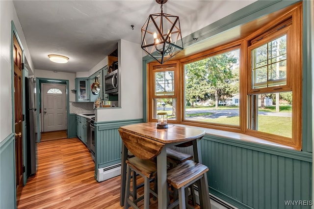 4306 Shimerville Rd, Clarence, NY 14031 - dining area featuring plenty of natural light, a chandelier, wainscoting, and light wood-style flooring