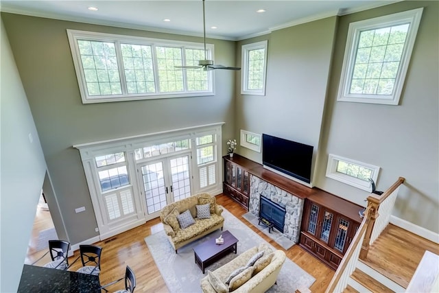 393 Mendon Center Rd, Mendon, NY 14472 - living room featuring a towering ceiling, wood finished floors, a stone fireplace, crown molding, and french doors