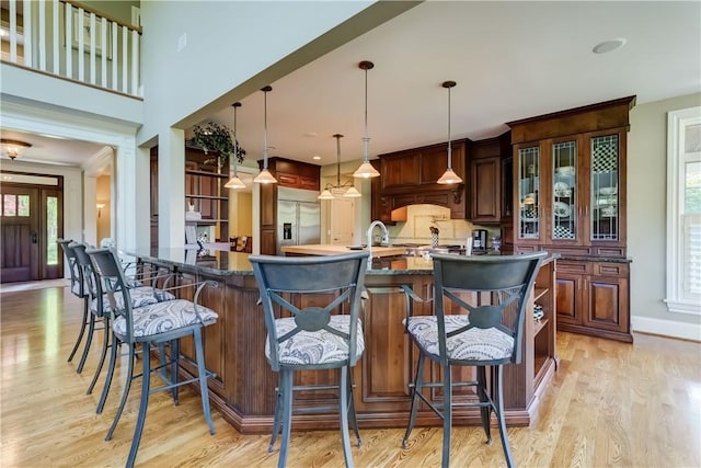 393 Mendon Center Rd, Mendon, NY 14472 - kitchen with stainless steel built in fridge, light wood finished floors, a kitchen breakfast bar, and dark stone counters