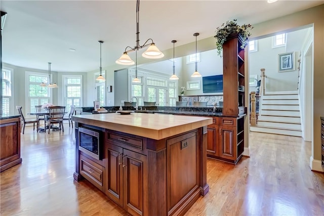 393 Mendon Center Rd, Mendon, NY 14472 - kitchen featuring stainless steel microwave, light wood-style flooring, a center island, and pendant lighting