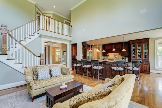 393 Mendon Center Rd, Mendon, NY 14472 - living area featuring ornamental molding, light wood-style floors, a high ceiling, and stairway