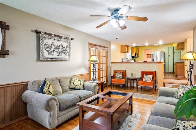 217 Red Lion Rd, Henrietta, NY 14467 - living room featuring a wainscoted wall, ceiling fan, wooden walls, light wood-style floors, and a textured ceiling