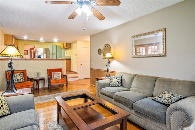 217 Red Lion Rd, Henrietta, NY 14467 - living room with light wood finished floors, a wainscoted wall, ceiling fan, a textured ceiling, and wood walls
