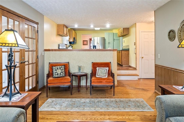 217 Red Lion Rd, Henrietta, NY 14467 - kitchen featuring white fridge with ice dispenser, a wainscoted wall, a textured ceiling, light wood-style floors, and a peninsula