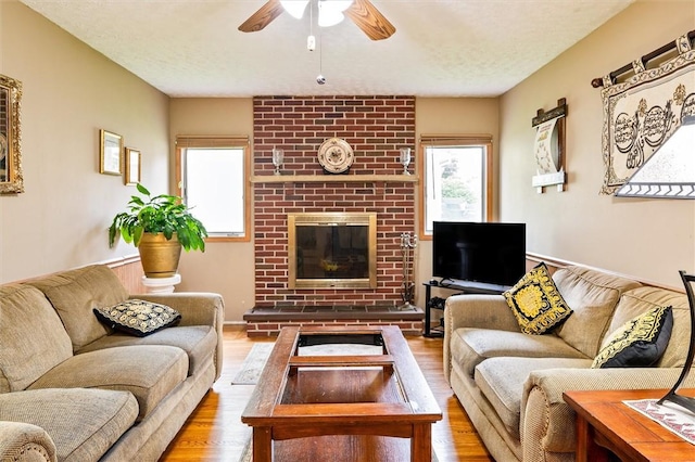 217 Red Lion Rd, Henrietta, NY 14467 - living room featuring a ceiling fan, wood finished floors, a brick fireplace, and a textured ceiling