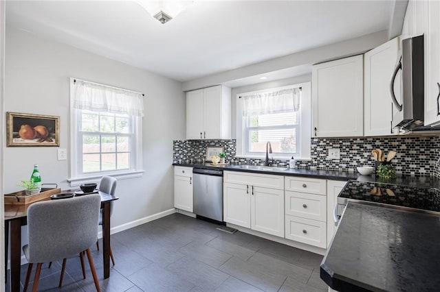 262 Barry Rd, Irondequoit, NY 14617 - kitchen with appliances with stainless steel finishes, dark countertops, tasteful backsplash, and white cabinetry