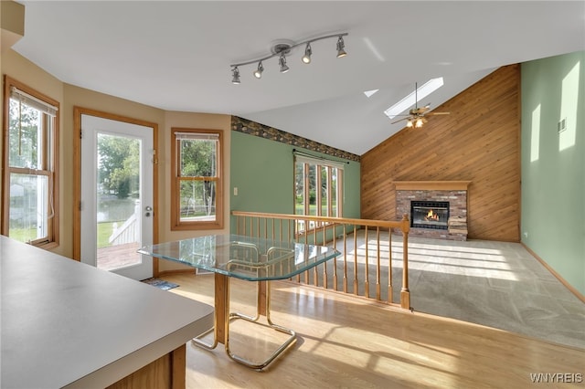 33 Sausalito Dr, Amherst, NY 14051 - unfurnished living room featuring a skylight, wooden walls, light wood-style flooring, vaulted ceiling, and a fireplace
