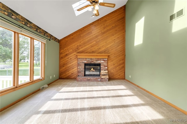 33 Sausalito Dr, Amherst, NY 14051 - unfurnished living room with wood walls, a brick fireplace, vaulted ceiling, a skylight, and a ceiling fan