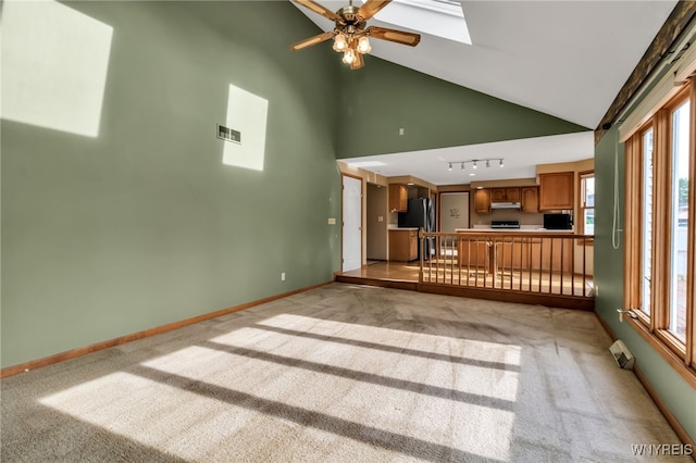 33 Sausalito Dr, Amherst, NY 14051 - unfurnished living room with ceiling fan, light colored carpet, a skylight, track lighting, and high vaulted ceiling