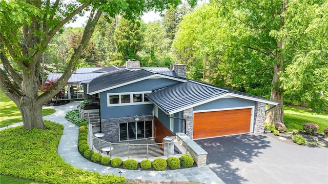 5 Elmwood Hill Ln, Brighton, NY 14610 - view of front of house featuring stone siding, a chimney, a standing seam roof, a metal roof, and a garage