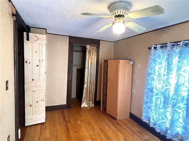 41 Evergreen St, Cortland, NY 13045 - unfurnished bedroom with wood-type flooring, ceiling fan, a textured ceiling, and a barn door