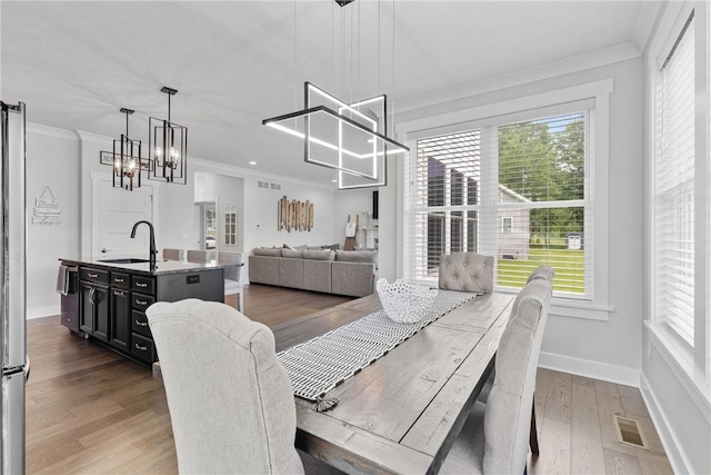 591 Whistlers Cove Ln, Greece, NY 14612 - dining space with ornamental molding, wood finished floors, and a chandelier