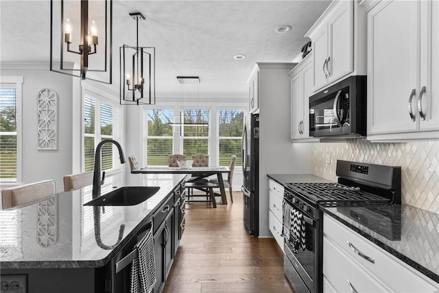 591 Whistlers Cove Ln, Greece, NY 14612 - kitchen with gas range oven, a chandelier, freestanding refrigerator, dark wood-type flooring, and crown molding