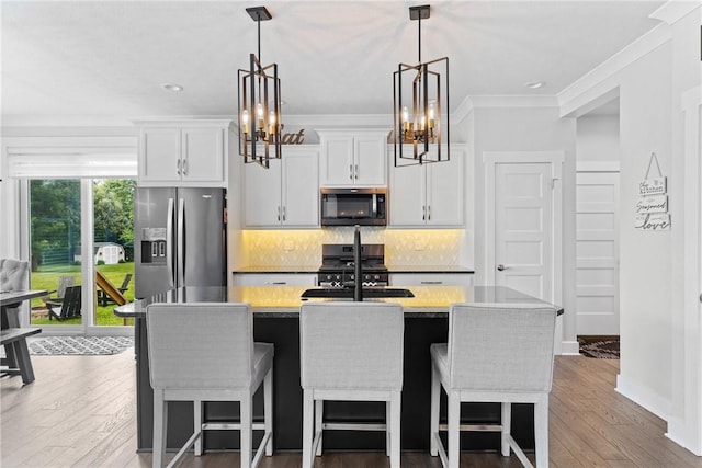 591 Whistlers Cove Ln, Greece, NY 14612 - kitchen with appliances with stainless steel finishes, a chandelier, a center island with sink, light countertops, and tasteful backsplash