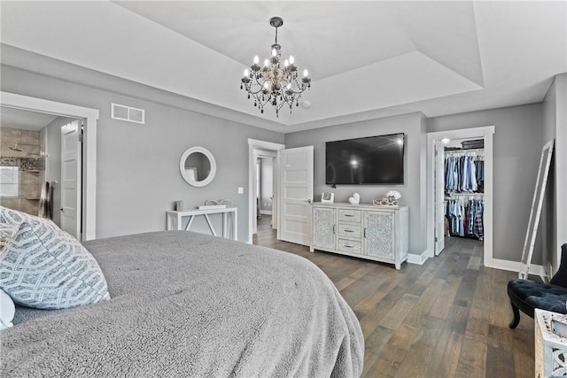 591 Whistlers Cove Ln, Greece, NY 14612 - bedroom featuring a walk in closet, a tray ceiling, dark wood-style flooring, a chandelier, and a closet