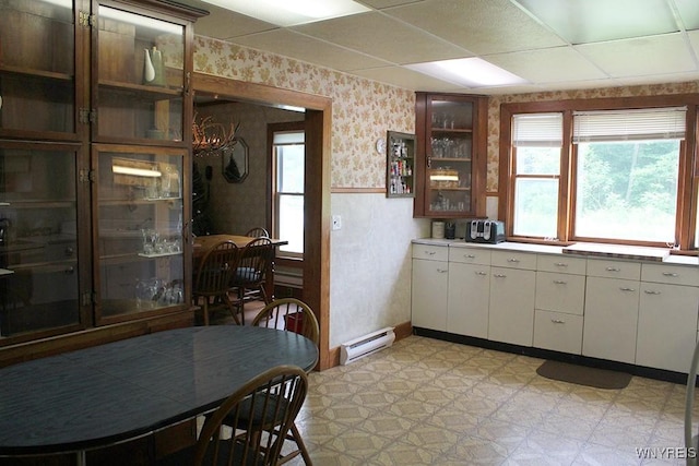 5046 Whig St, Little Valley, NY 14779 - kitchen featuring wallpapered walls, light flooring, a baseboard radiator, glass insert cabinets, and white cabinets