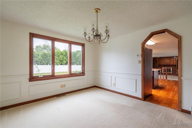 64 Bywater Dr, Amherst, NY 14068 - carpeted empty room featuring a wainscoted wall, a chandelier, a textured ceiling, and arched walkways