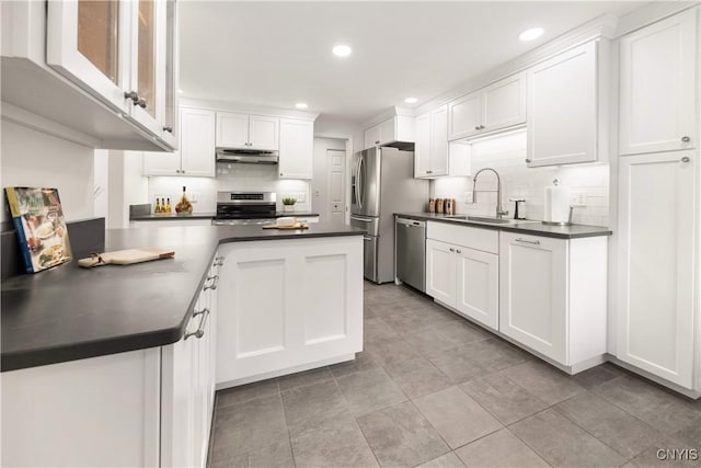 4797 Huntwood, Manlius, NY 13104 - kitchen with appliances with stainless steel finishes, under cabinet range hood, dark countertops, decorative backsplash, and white cabinetry
