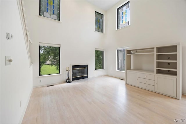 4797 Huntwood, Manlius, NY 13104 - unfurnished living room with a towering ceiling, healthy amount of natural light, light wood-style floors, and a glass covered fireplace