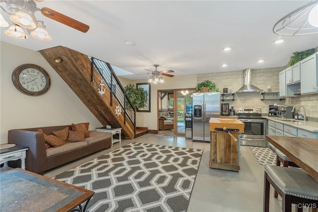 2012 Pleasant Ave, Vienna, NY 13308 - kitchen featuring stainless steel appliances, ceiling fan, wall chimney range hood, tasteful backsplash, and finished concrete floors
