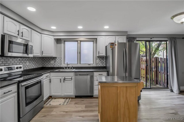 351 Charlesgate Cir, Amherst, NY 14051 - kitchen with appliances with stainless steel finishes, white cabinetry, light wood-style floors, dark countertops, and decorative backsplash