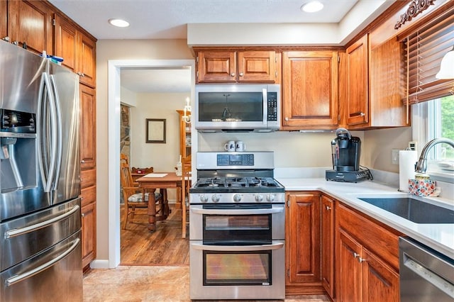 99 Old English Dr, Greece, NY 14616 - kitchen featuring appliances with stainless steel finishes, light countertops, brown cabinets, and recessed lighting