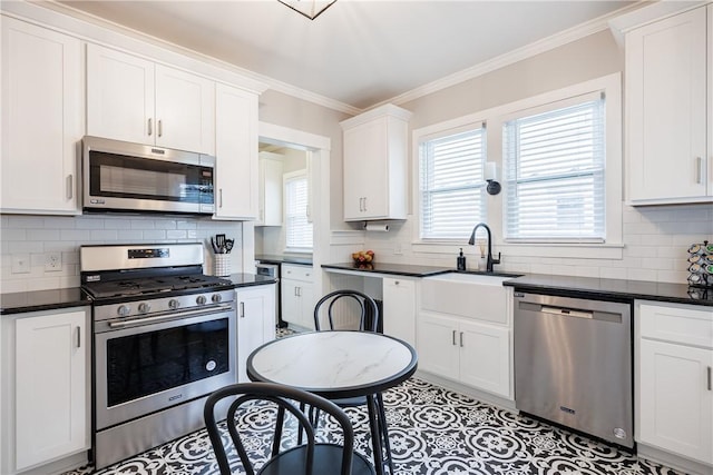 905 W Center St, Ridgeway, NY 14103 - kitchen with stainless steel appliances, dark countertops, backsplash, white cabinets, and ornamental molding