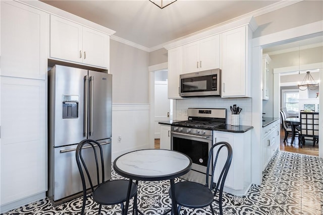 905 W Center St, Ridgeway, NY 14103 - kitchen with appliances with stainless steel finishes, dark countertops, white cabinets, crown molding, and decorative backsplash